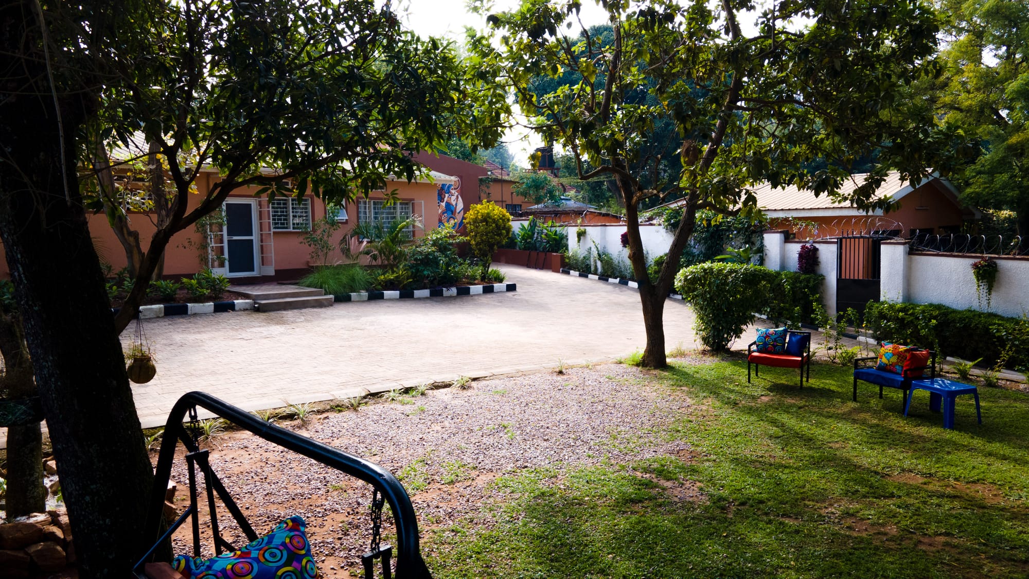 The tree-shaded driveway and cushioned garden seating at the entrance