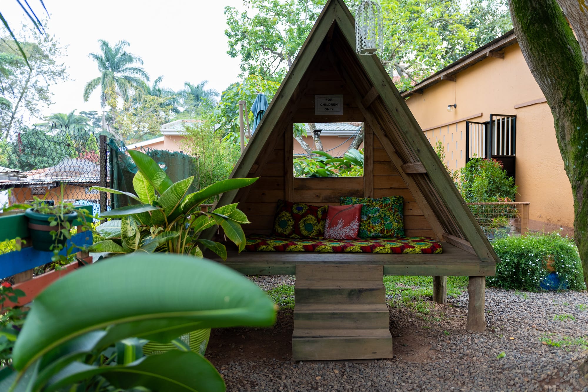 The 'for children only' A-frame reading hut with African print cushions, set among the garden greenery