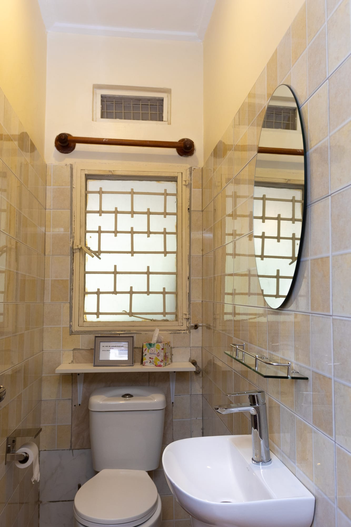 A tiled en-suite bathroom with an oval mirror and a frosted window