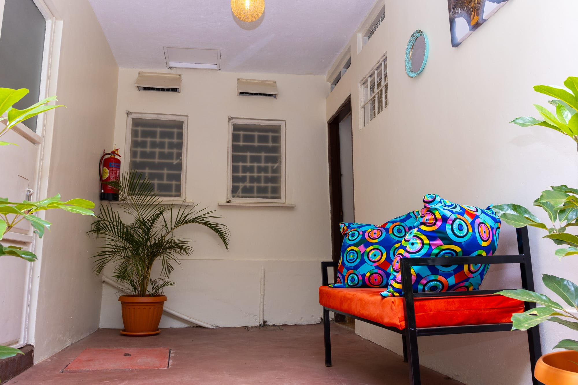 The B&B entrance porch with an orange bench and bright patterned cushions among potted plants