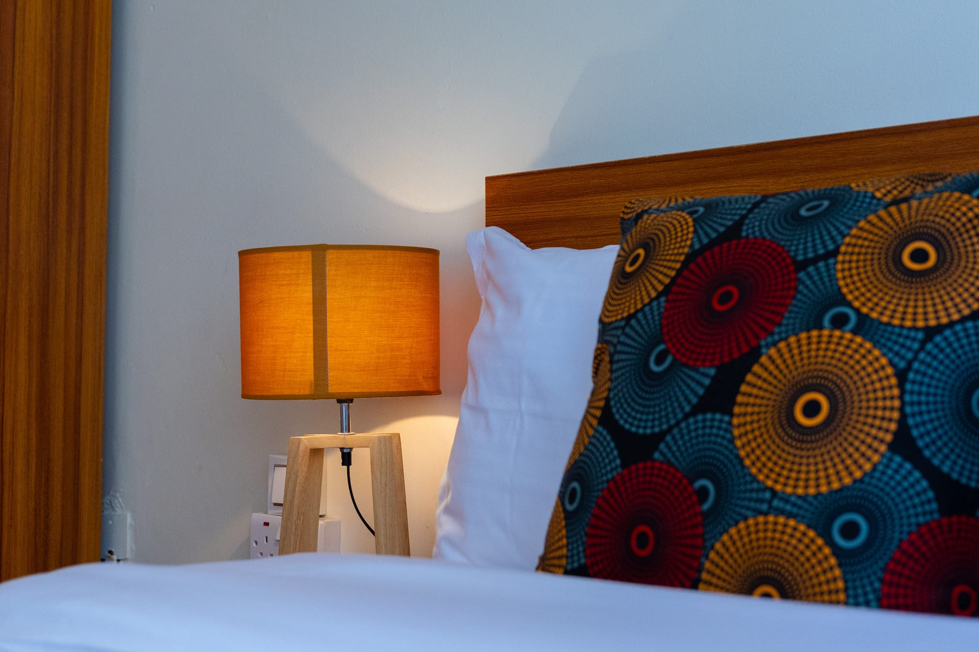 Warm bedside lamplight against a wooden headboard