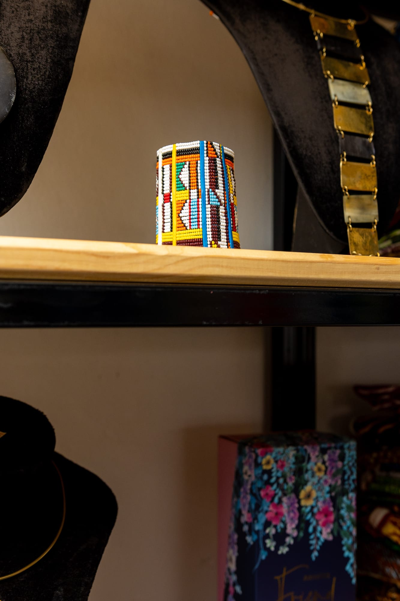 A brightly beaded Maasai cylinder cuff displayed on a shelf