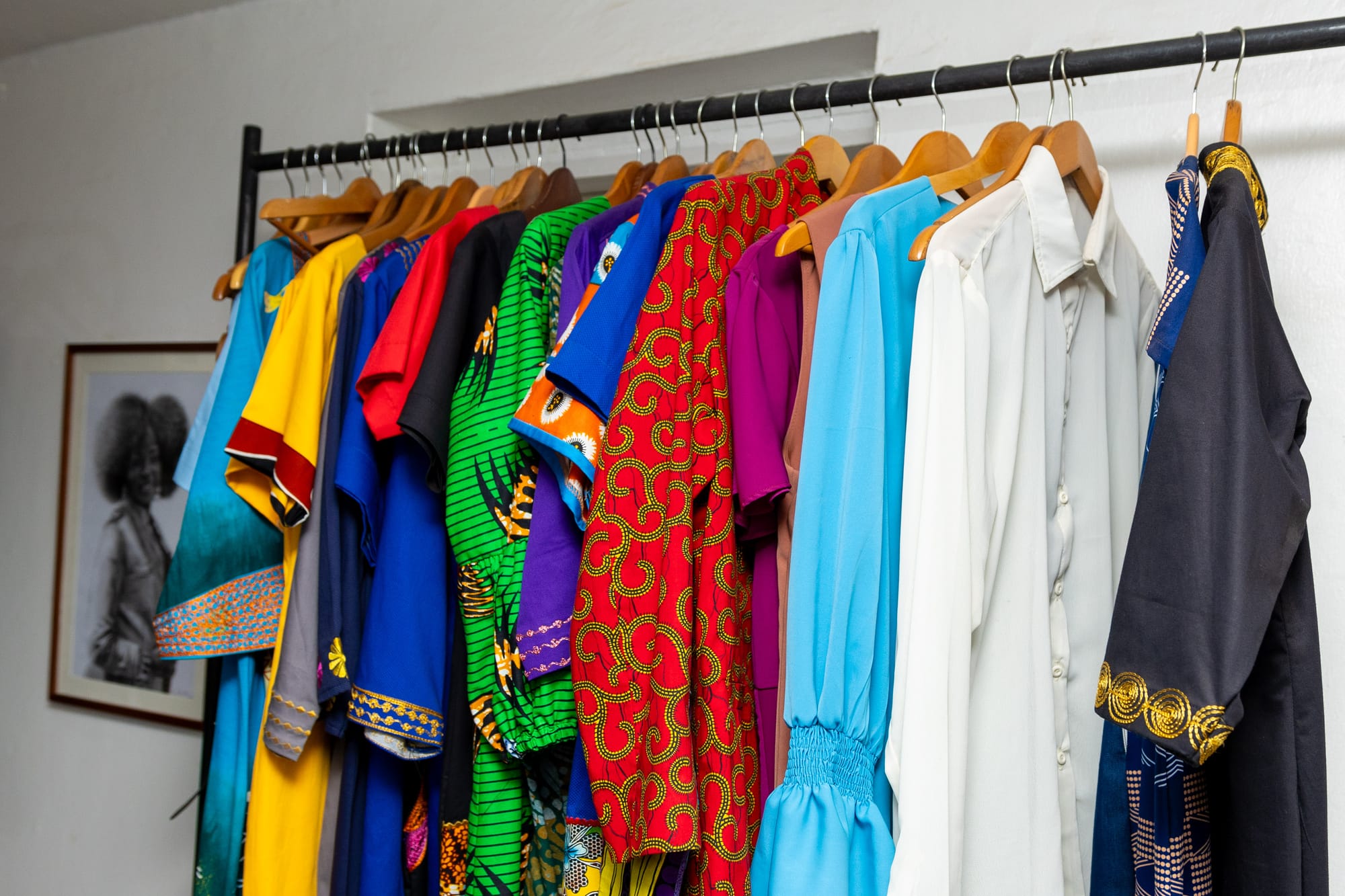 A rail of colourful African-print and tailored garments on wooden hangers