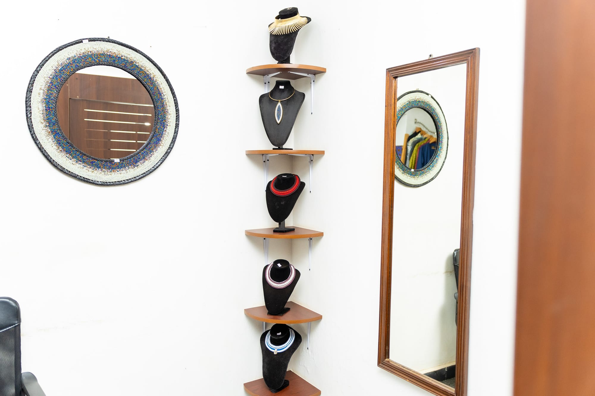 A corner shelf of beaded necklaces between two beaded-frame mirrors