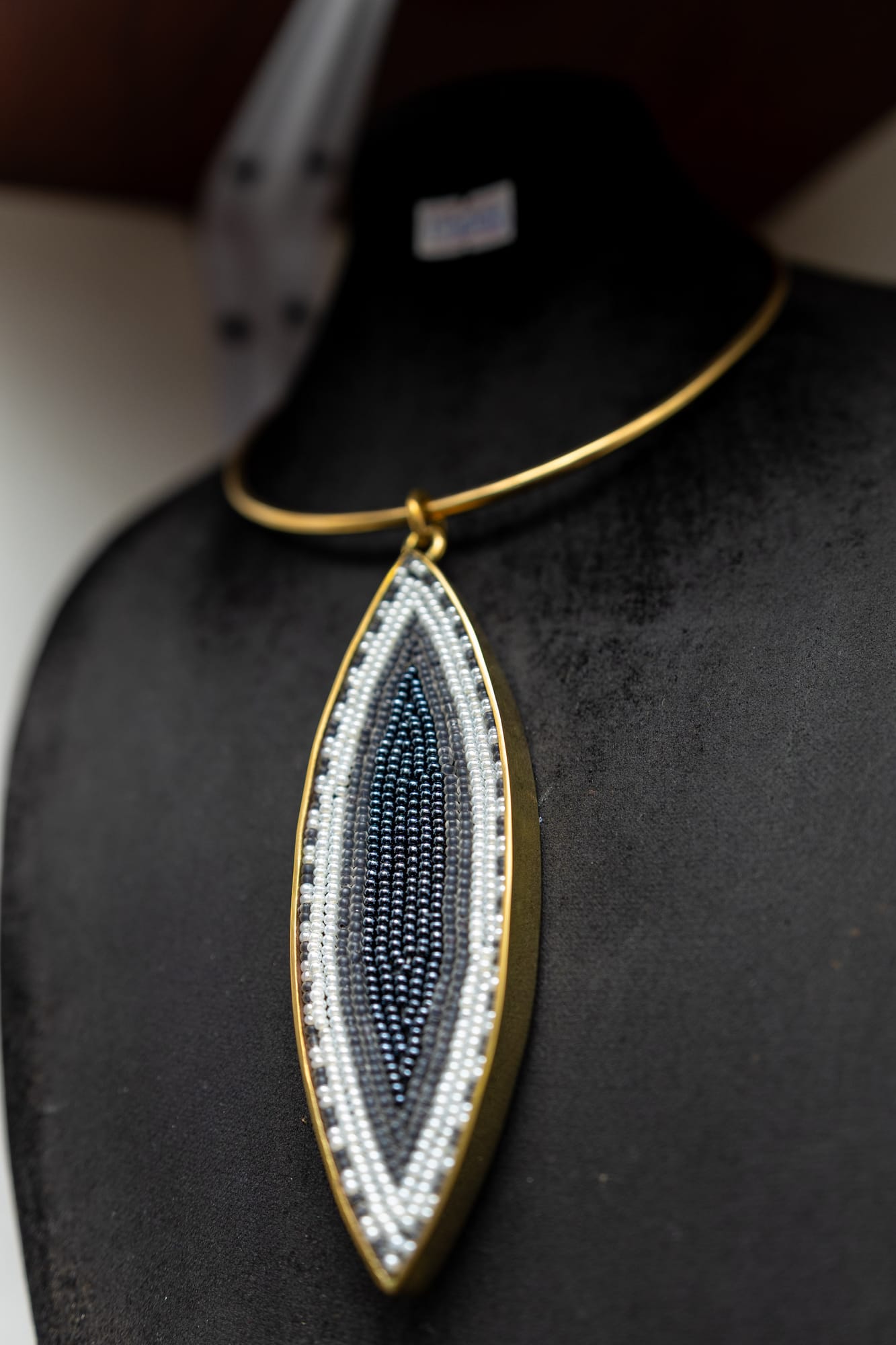 A beaded marquise pendant in blue, grey and white on a brass collar
