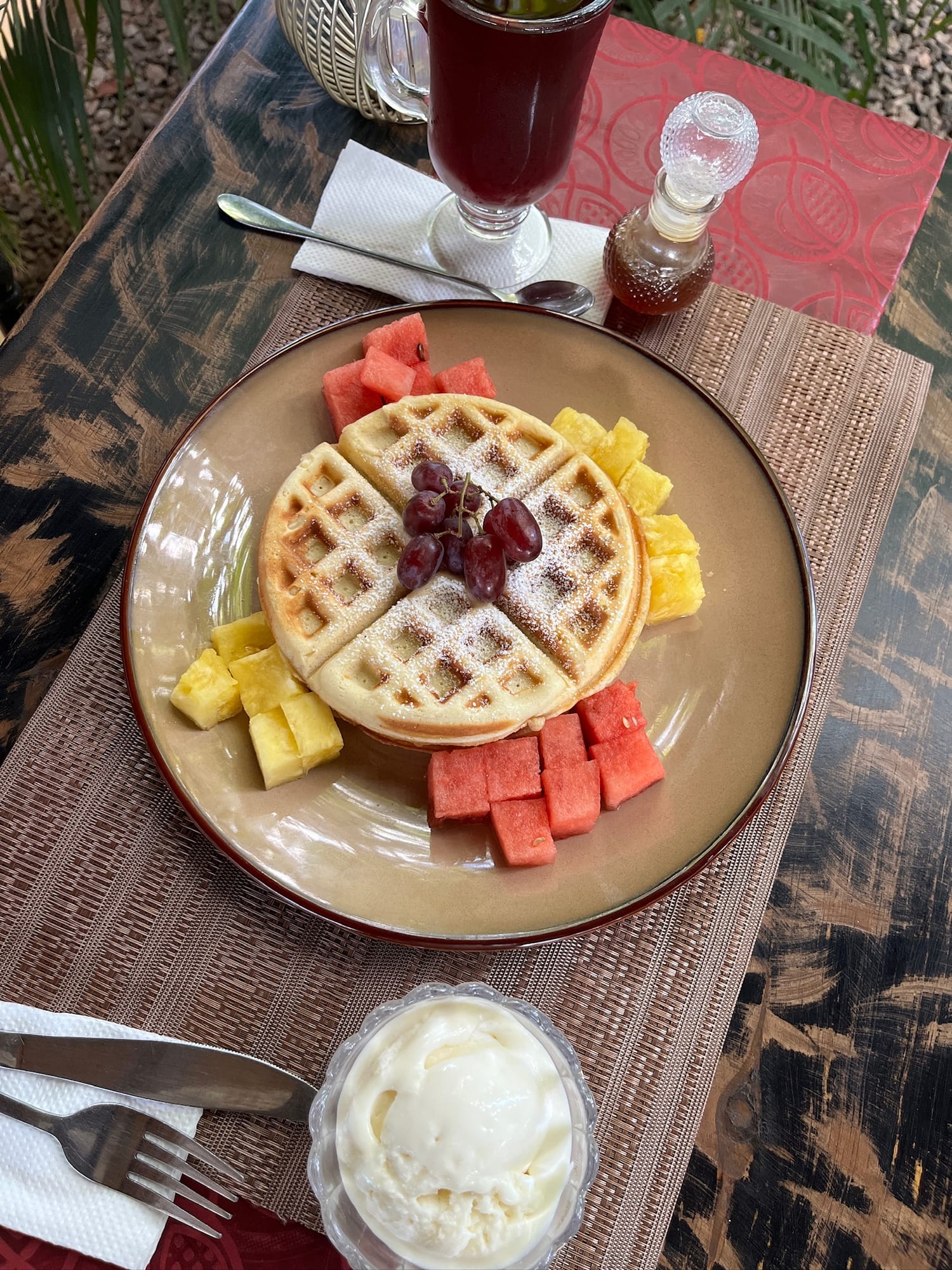 Golden waffle dusted with sugar, fresh fruit and cream