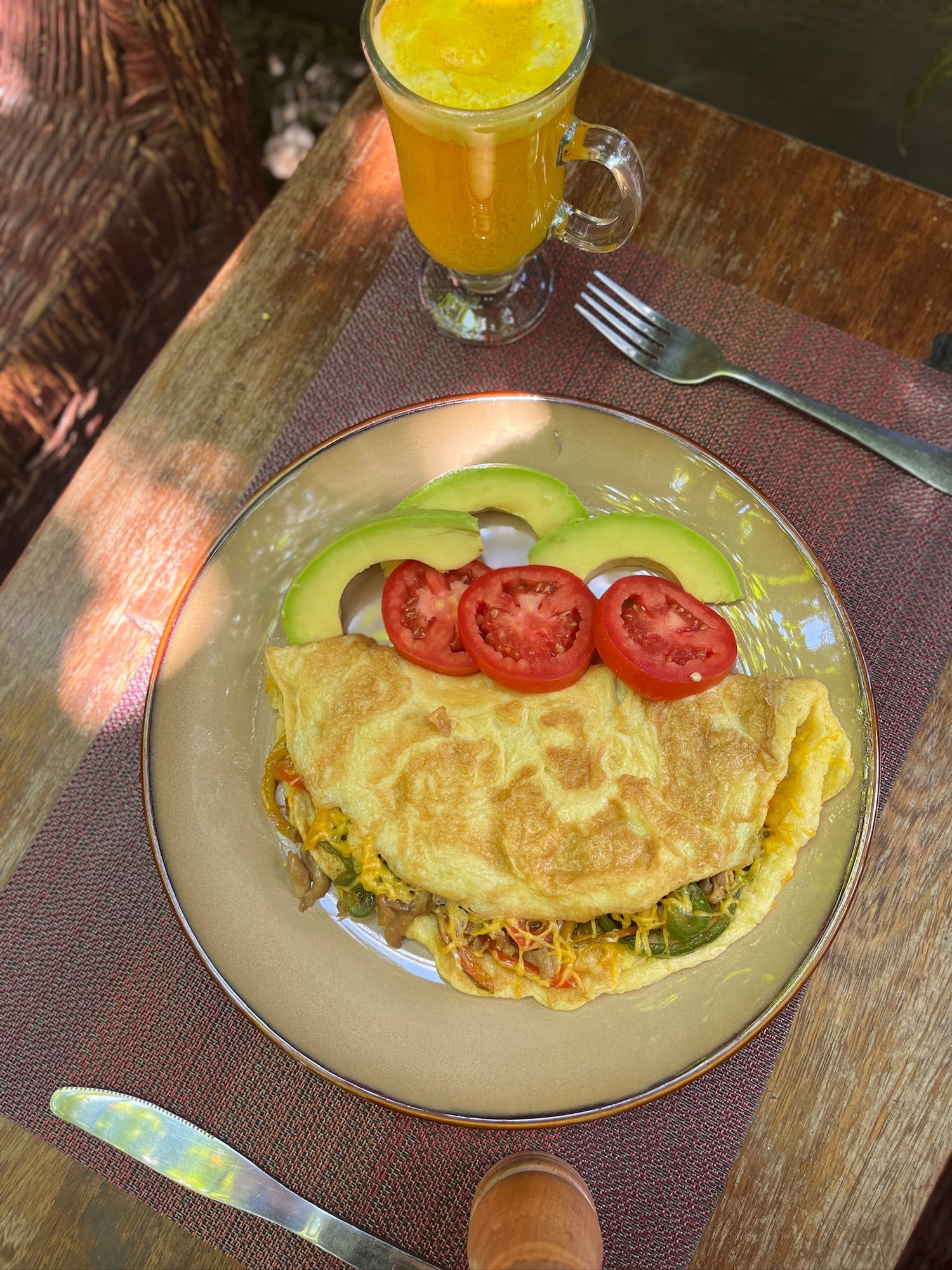 Folded vegetable omelette with avocado, tomato and a turmeric drink