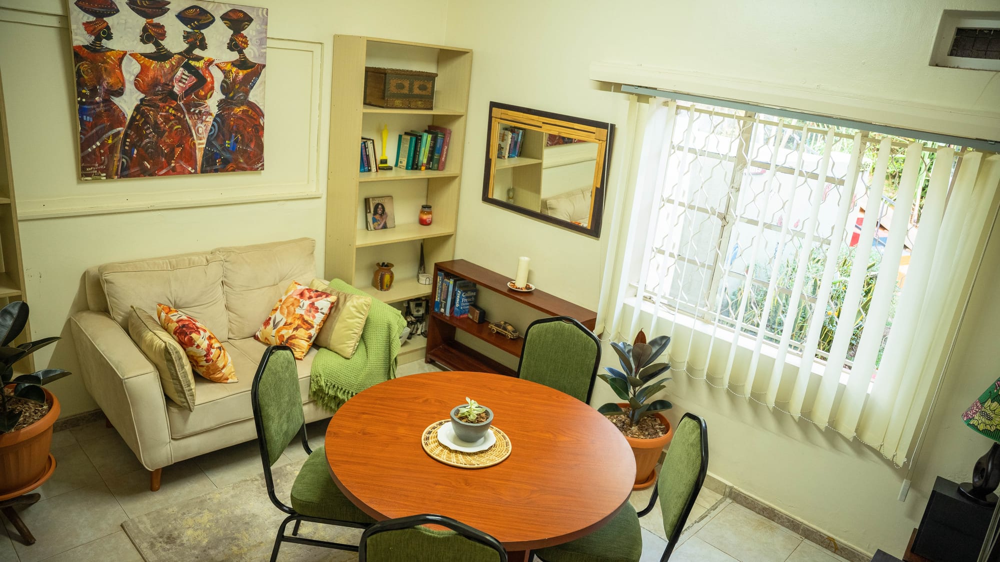 A breakout nook with a round table and green chairs, a reading sofa and bookshelves