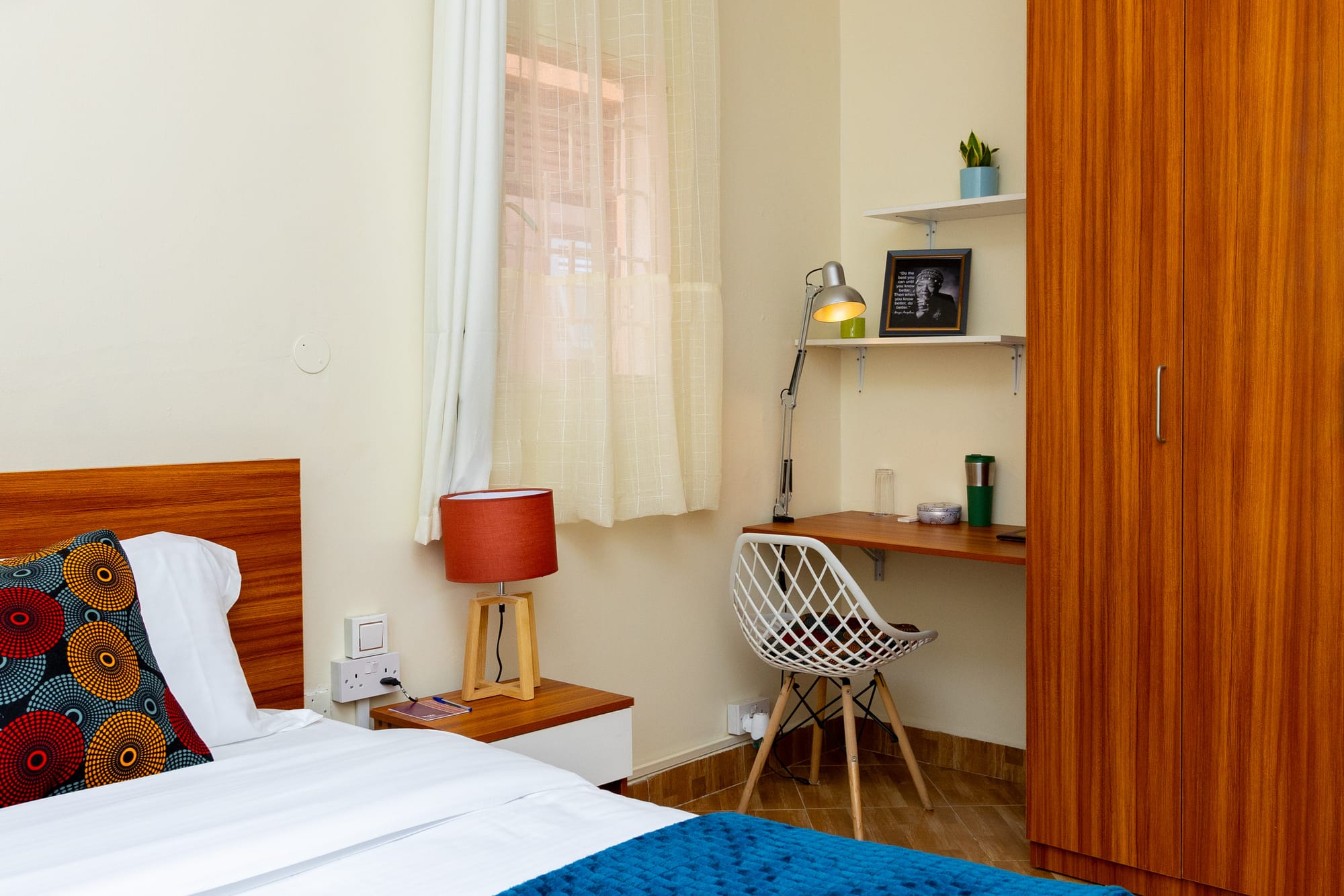 Deluxe Room — the bed beside a wooden work desk, reading lamp and shelf