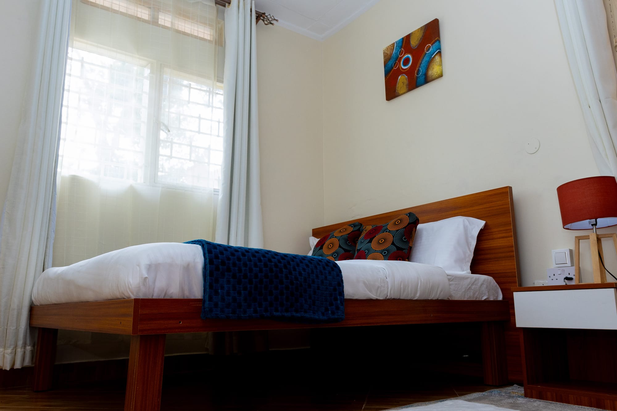 Deluxe Room — the bed and headboard with framed art and a warm red lamp
