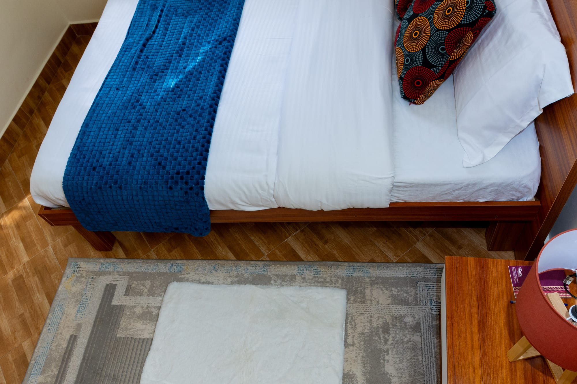 Deluxe Room — the bed seen from above with a blue throw and patterned rug