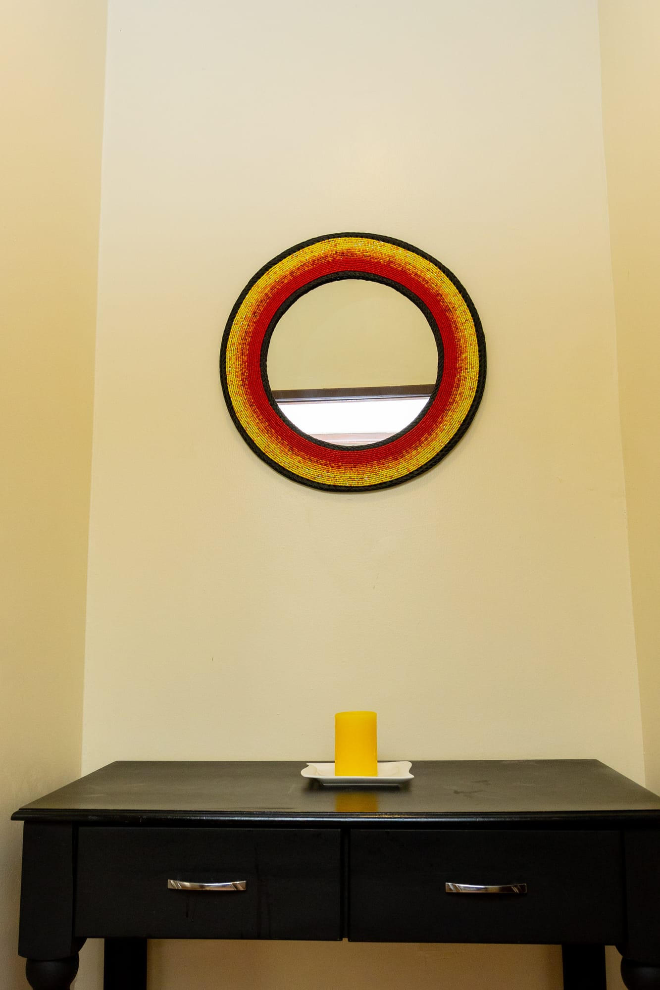 Deluxe Room — a beaded Ugandan-flag mirror above a black console table