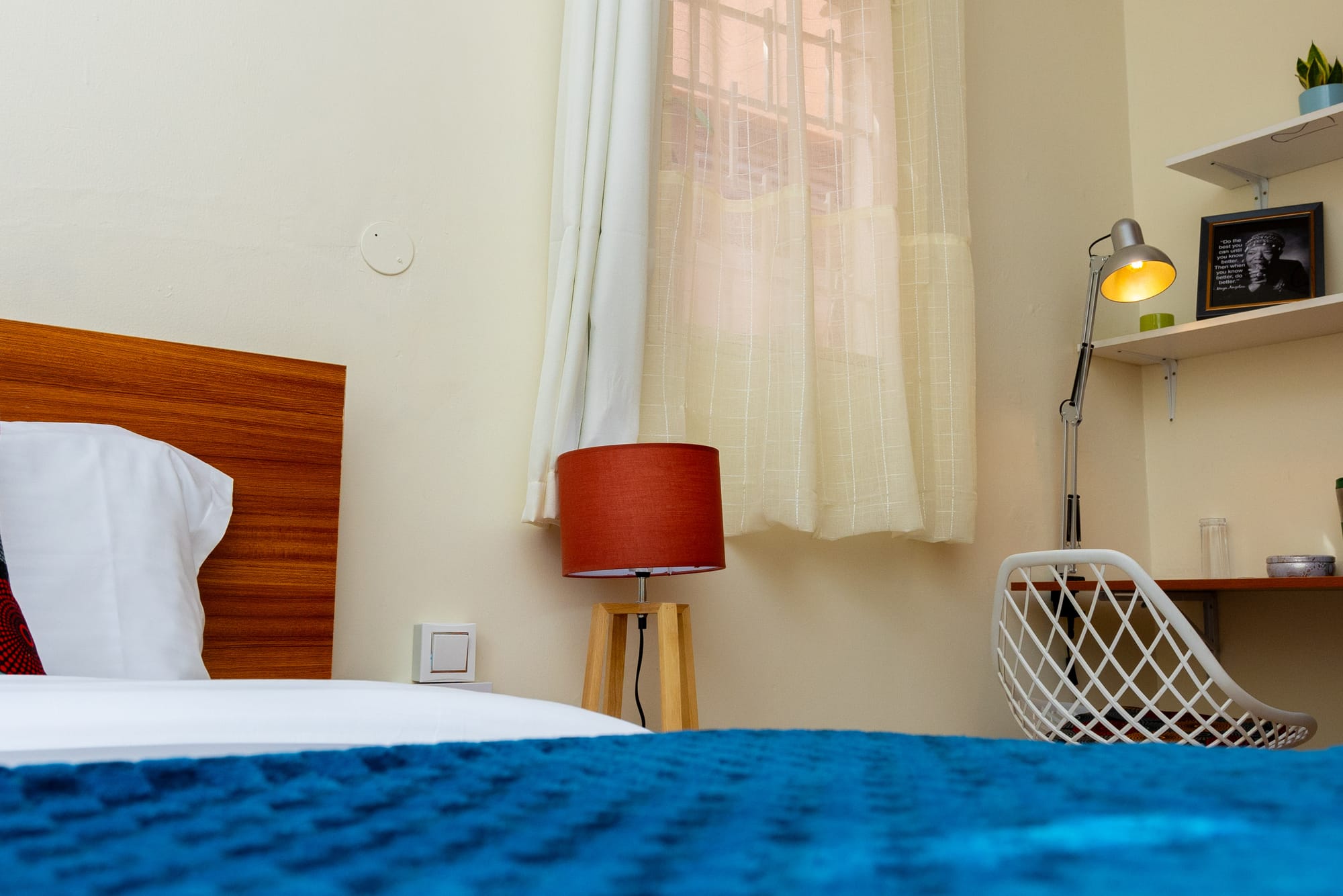 Deluxe Room — close-up of bold African print cushions against the wooden headboard