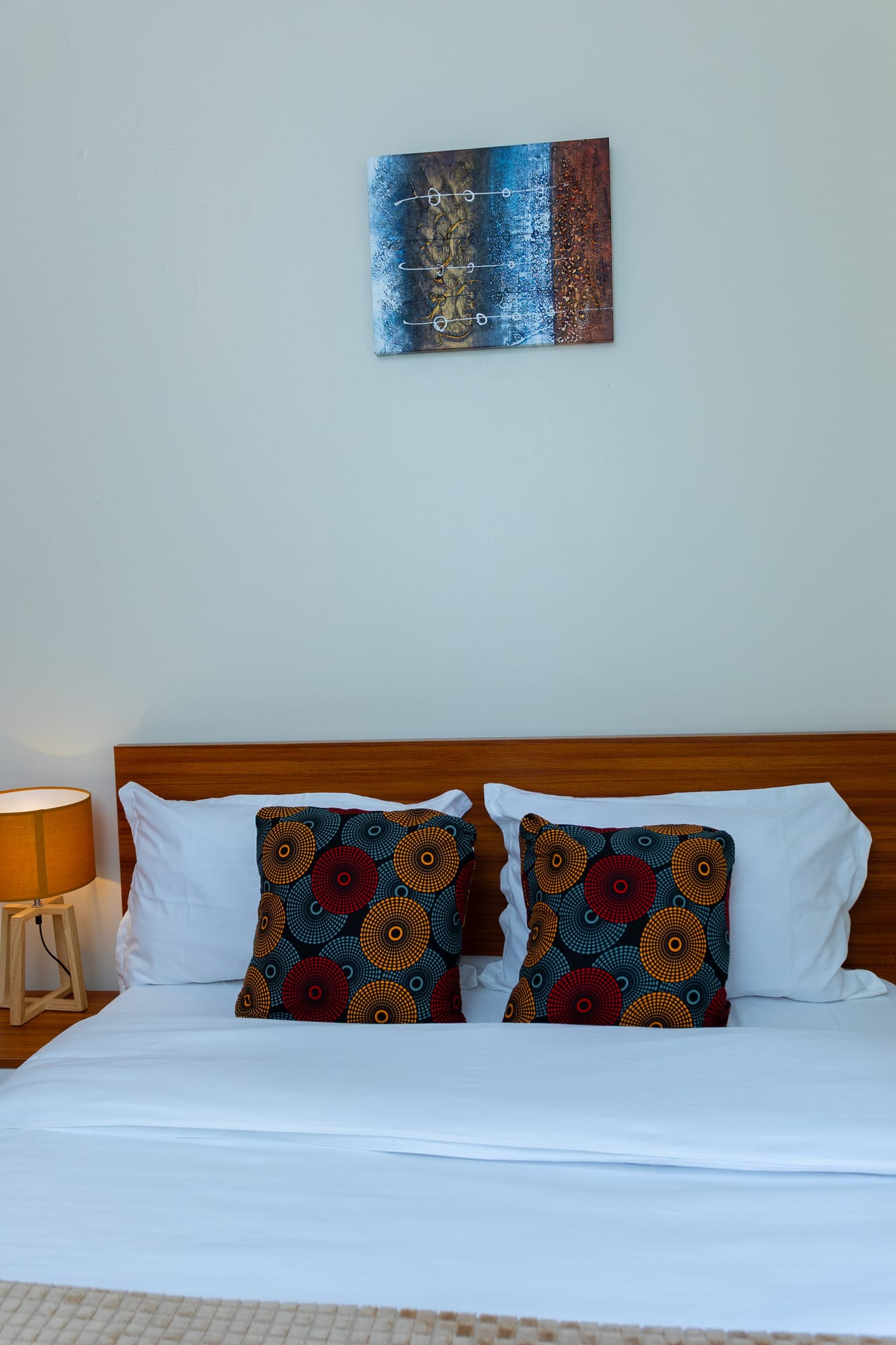 Deluxe Room — the dressed bed with patterned cushions and framed art above