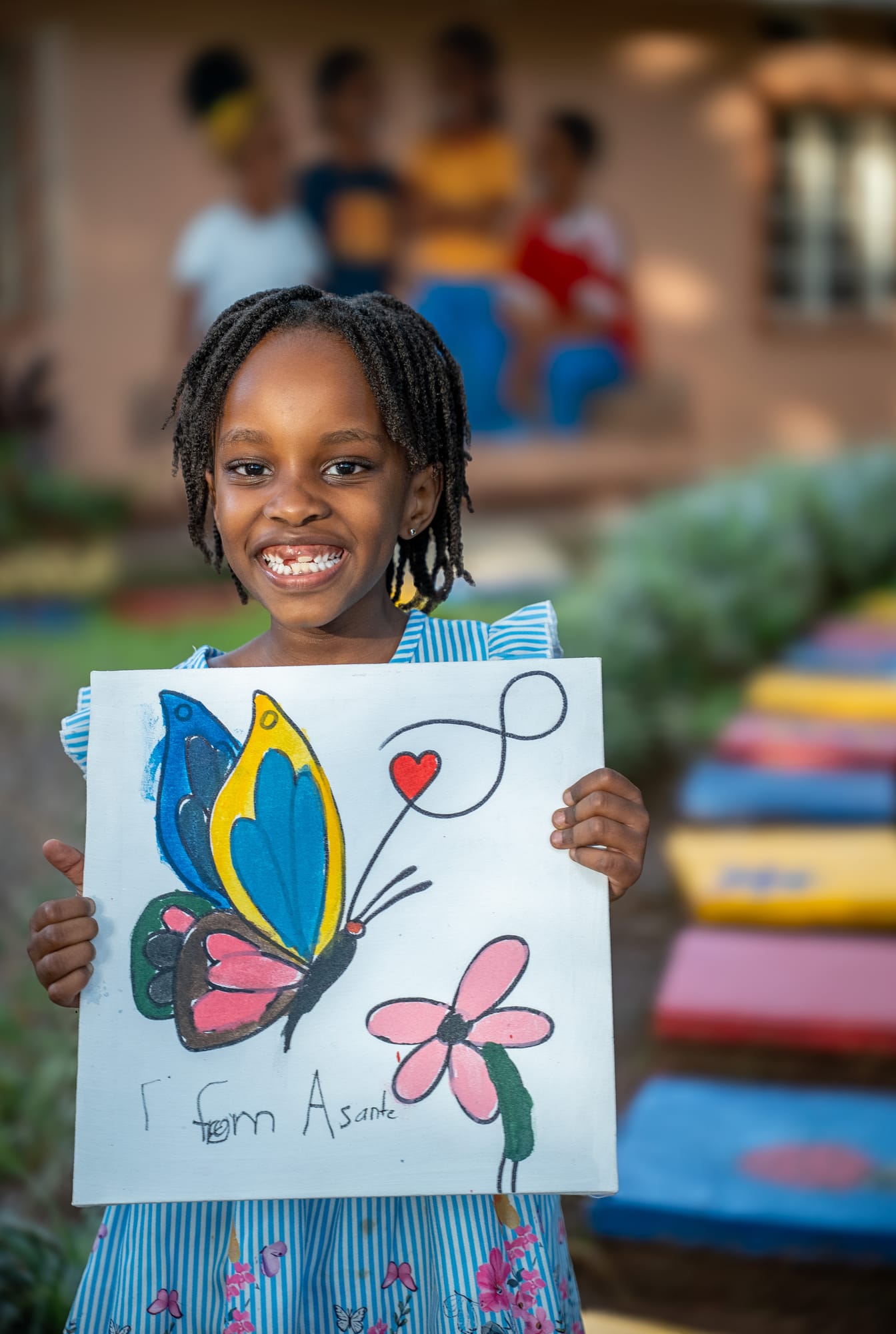 A young maker holding up her finished butterfly canvas