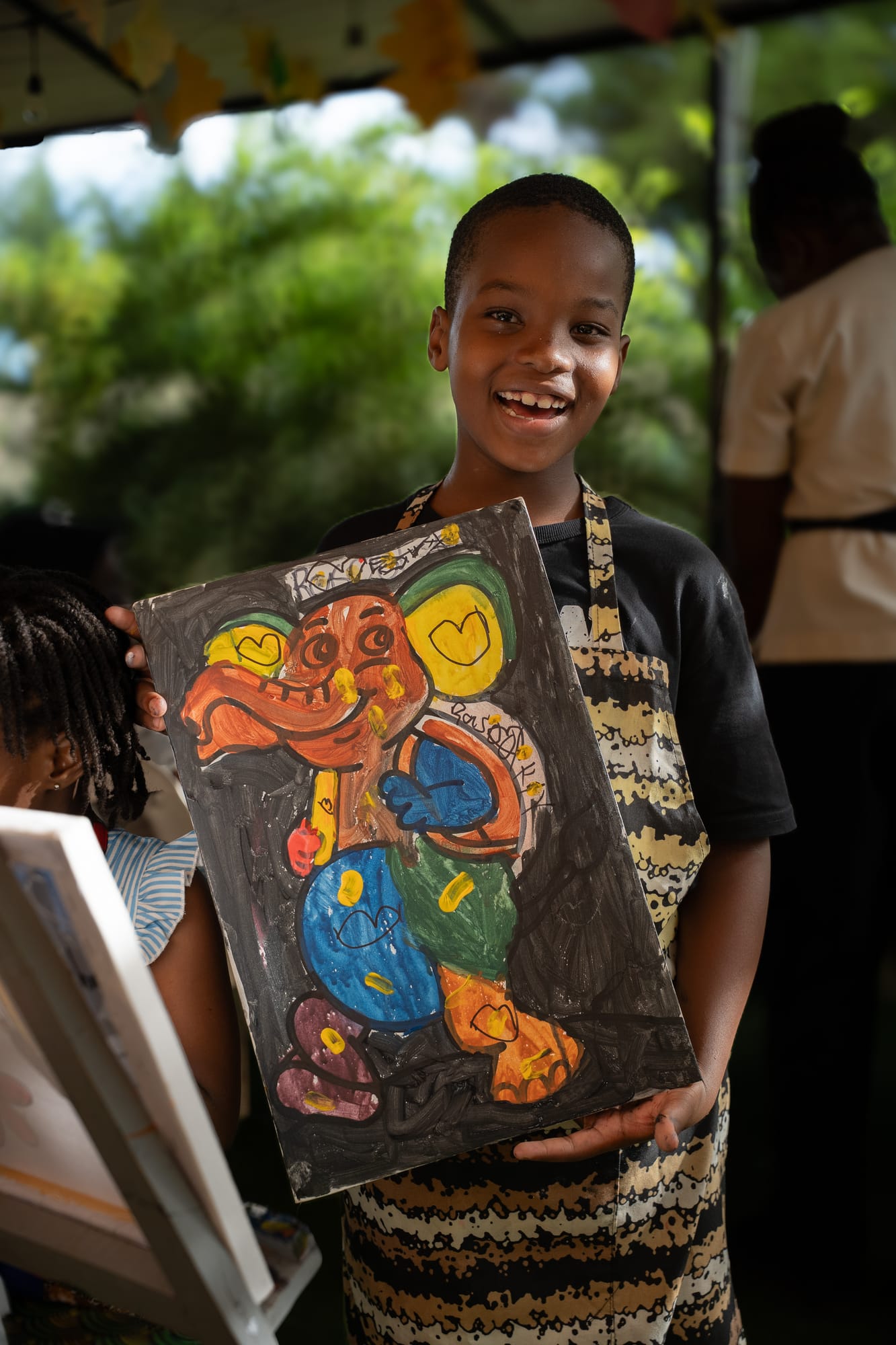 A proud young painter showing his elephant canvas