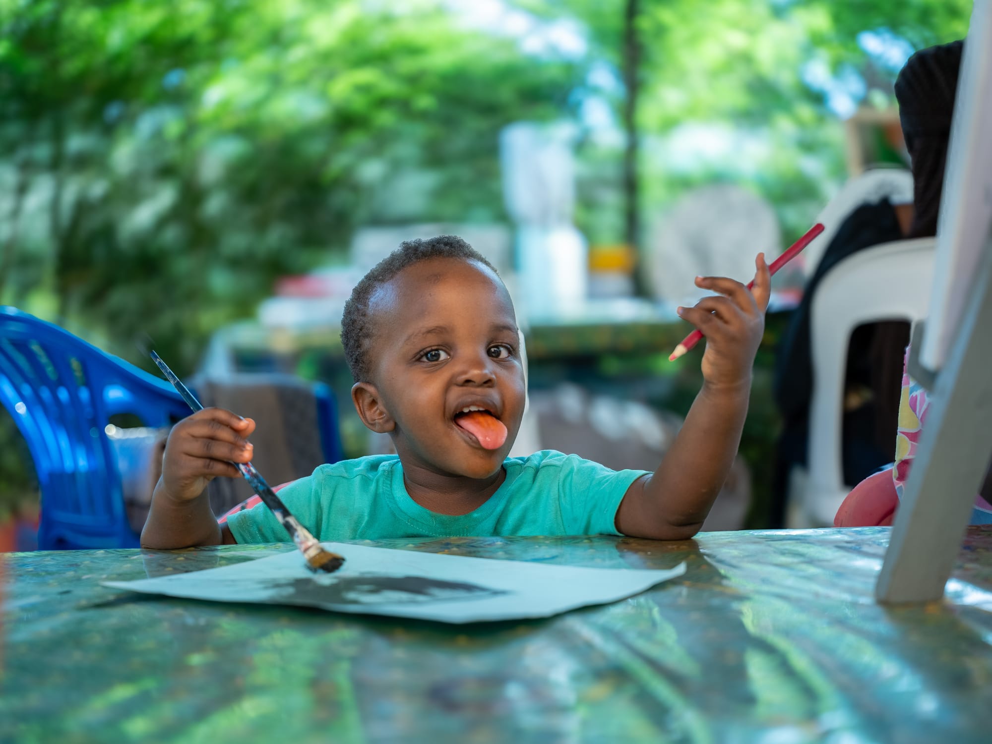 A young painter mid-masterpiece, tongue out in concentration