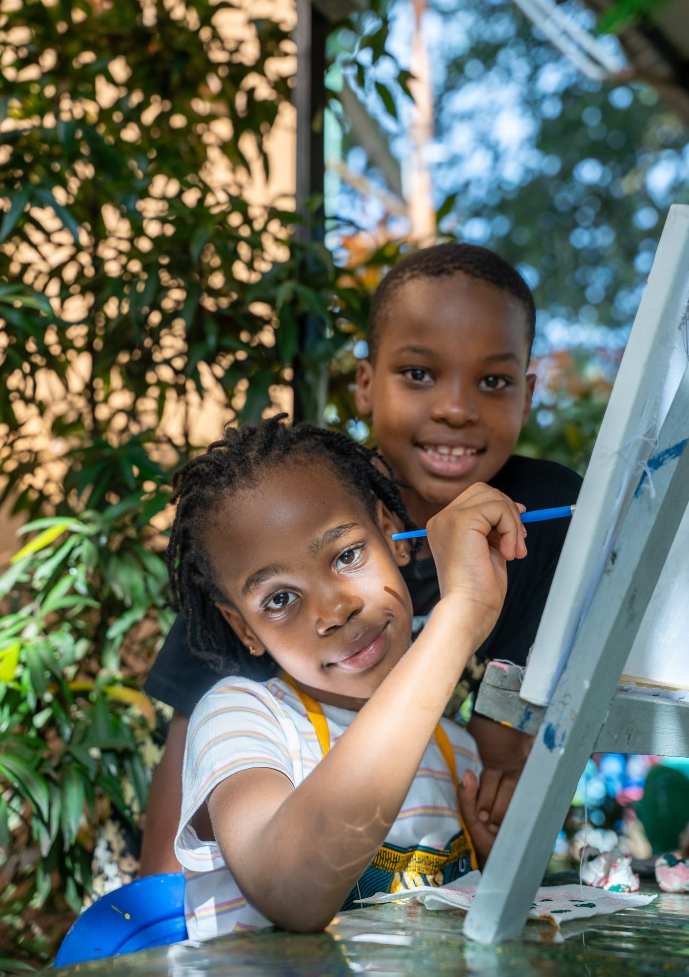 Two children painting side by side at easels