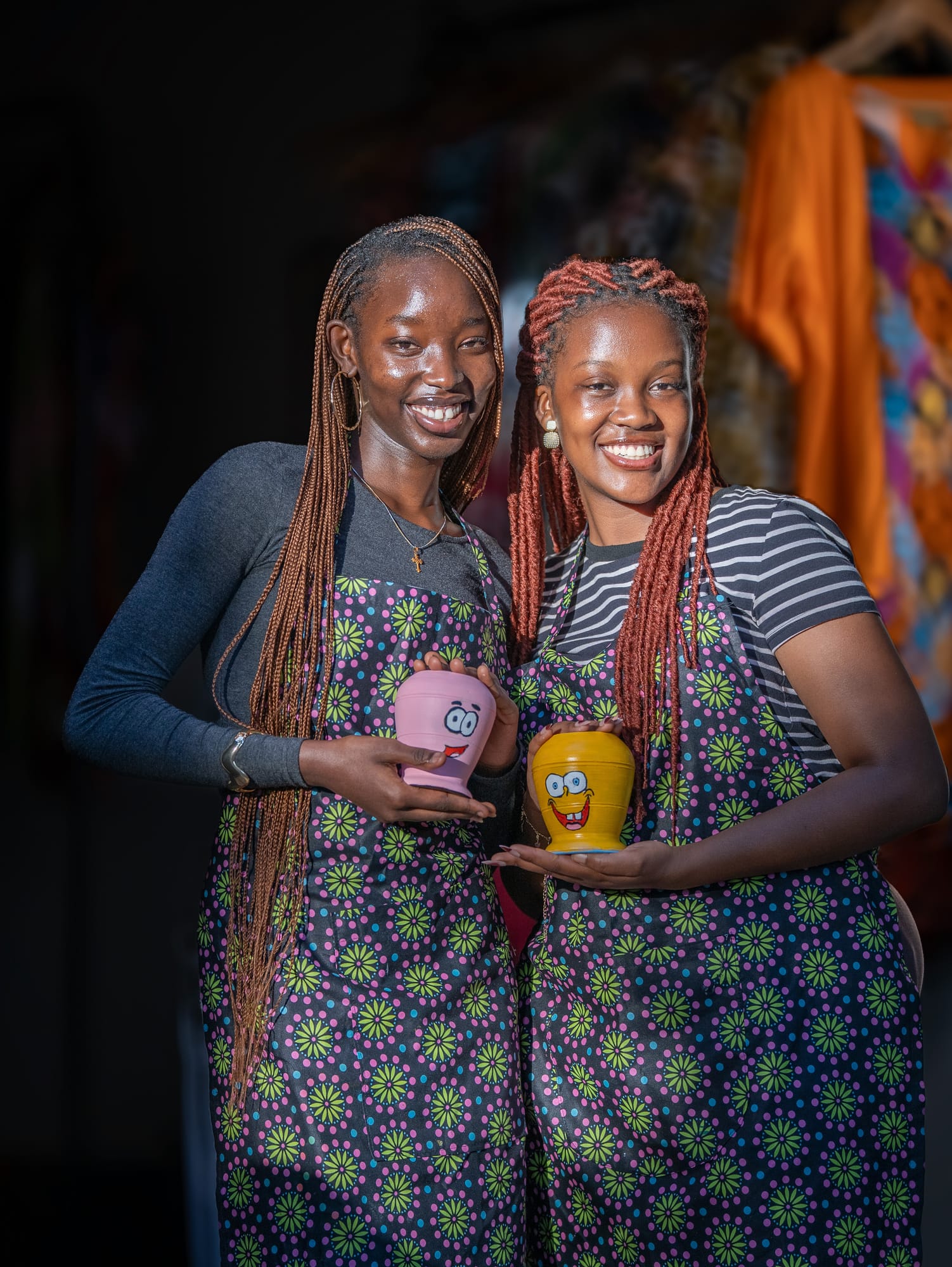 Two makers showing the cups they painted