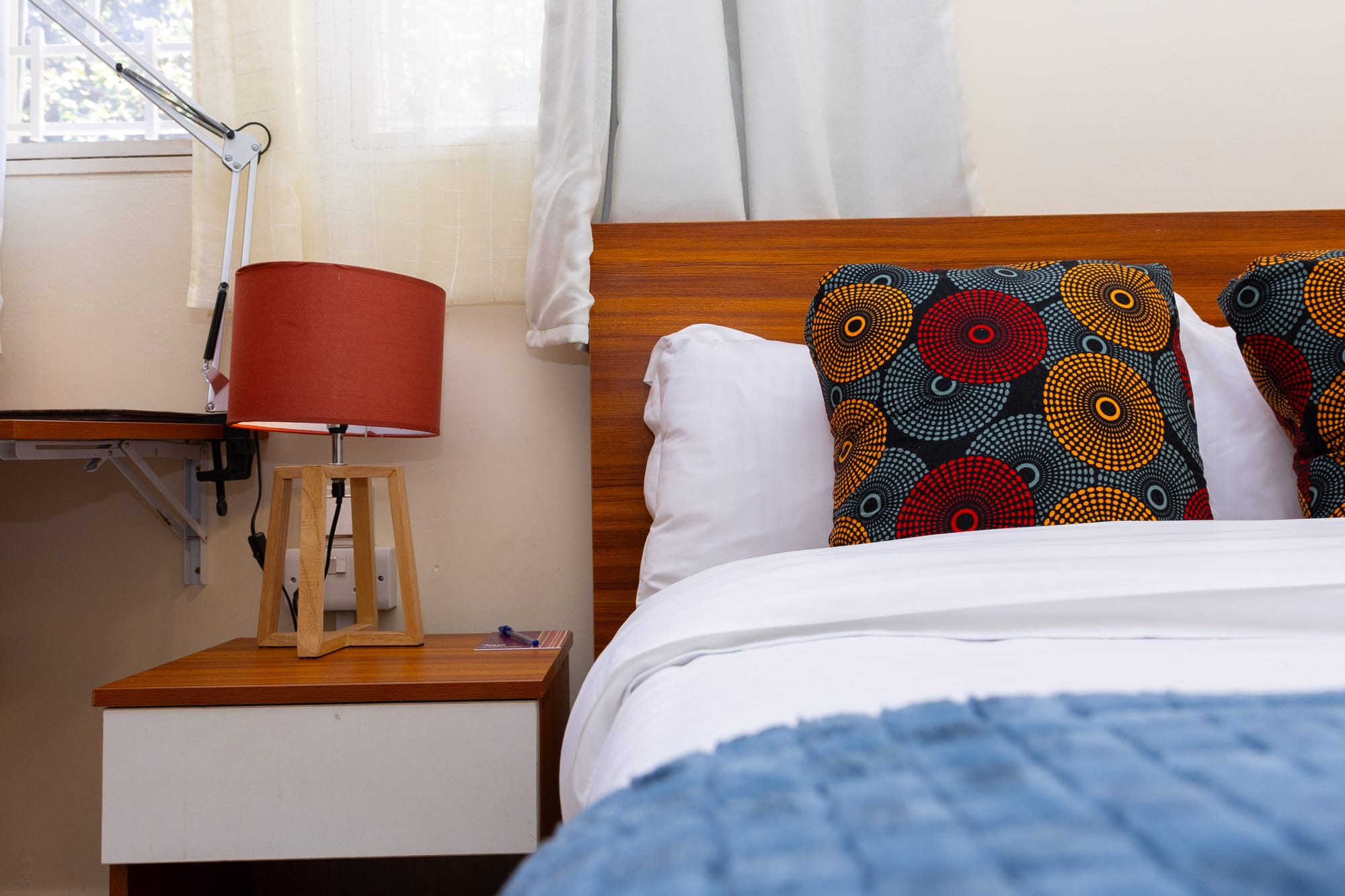 Standard Room — the bed with a warm red lamp on the bedside table