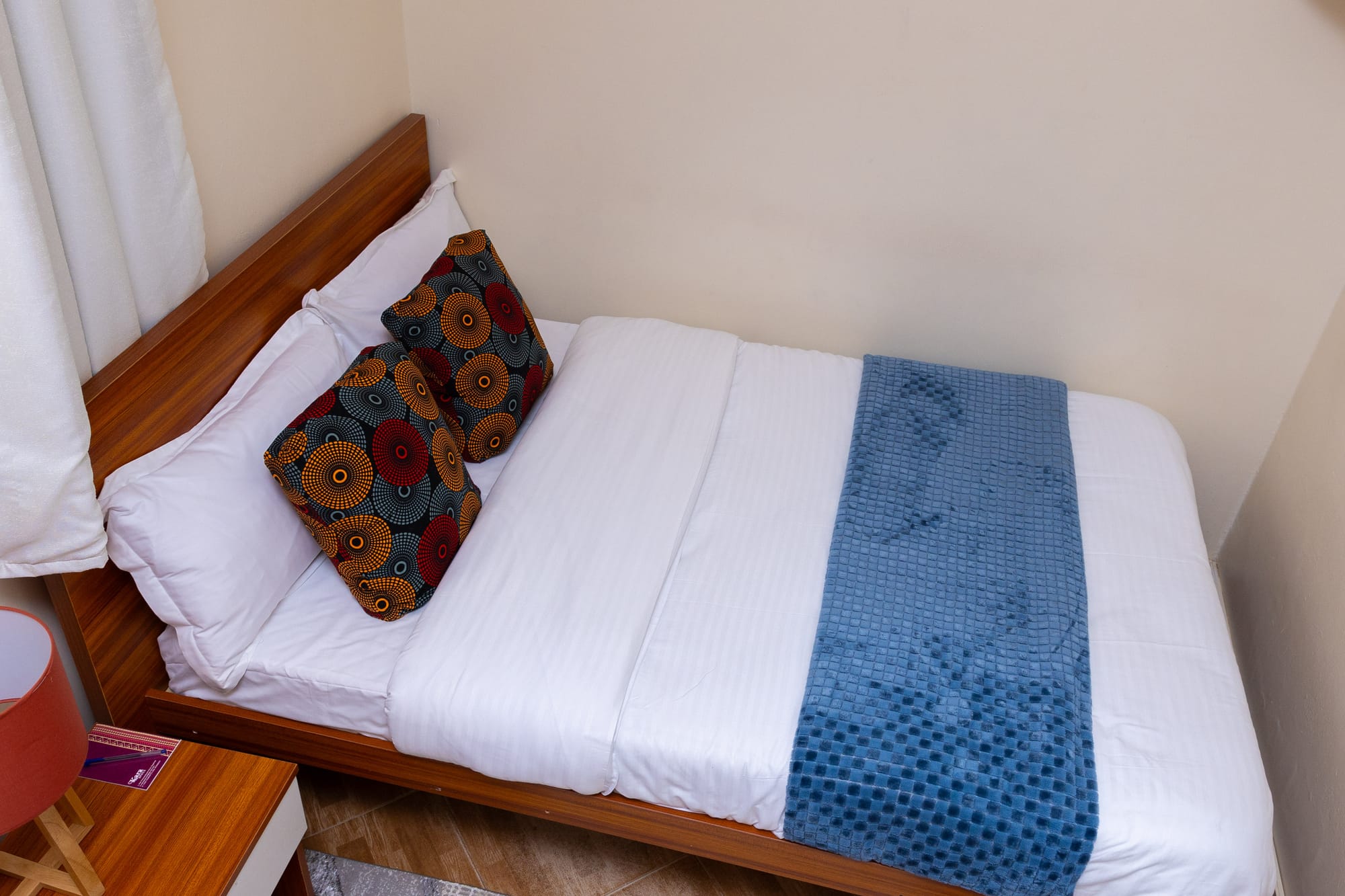 Standard Room — the bed seen from above, dressed in white with a blue throw